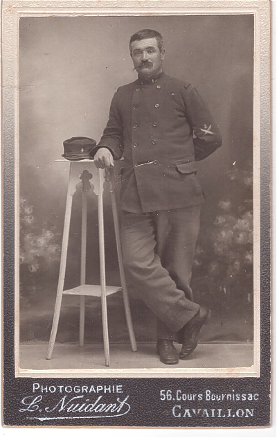 Soldat debout près d'une sellette où il a posé son képi