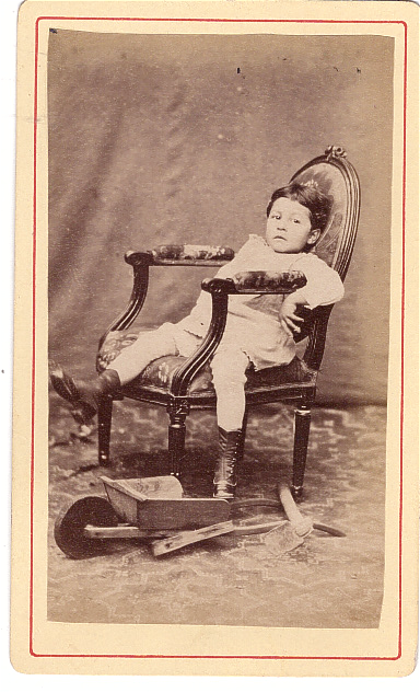 Enfant avachi dans un fauteuil avec, à ses pieds, une petite brouette 