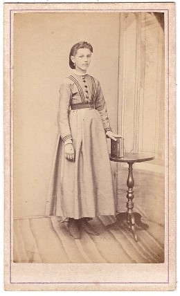 Jeune femme debout, une main posée sur un album de photographies