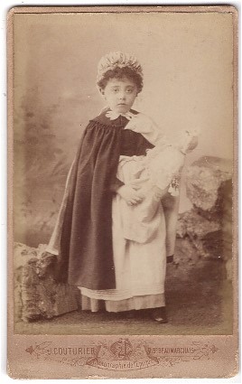 Petite fille costumée en nourrice tenant sa poupée 