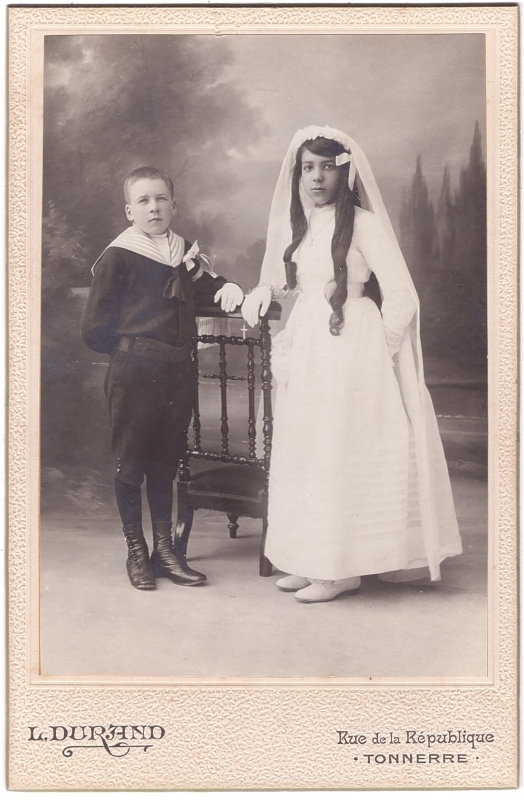 Communiante posant à côté de son jeune frère vêtu d'une marinière