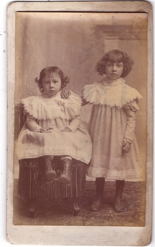 Deux soeurs, la plus jeune assise sur une chaise
