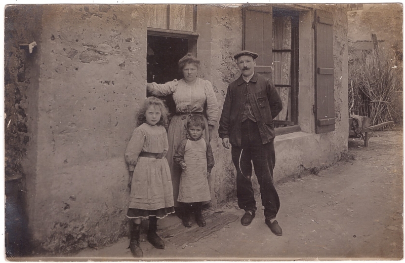 Couple et leurs deux enfants posant à l'entrée de leur maison