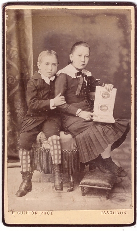 Garçon posant à côté de sa soeur qui tient un album de photographies