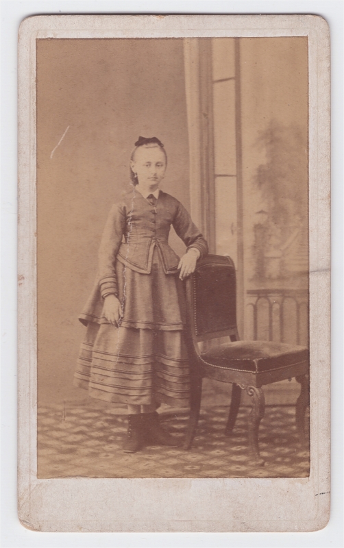 Jeune fille debout près d'une chaise