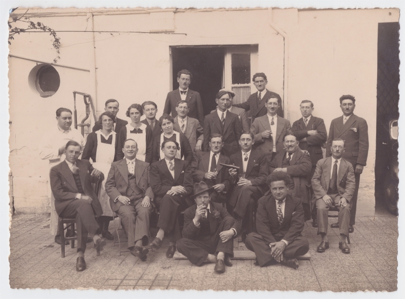 Groupe d'une vingtaine d'hommes posant avec le personnel d'un restaurant