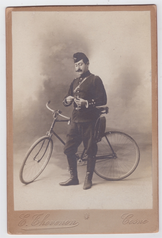 Militaire (vaguemestre ?) posant en atelier à côté de sa bicycylette