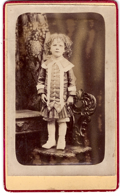 Enfant aux cheveux frisés debout sur une chaise