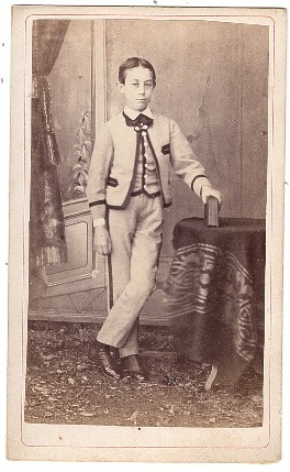 Grand garçon debout, une main posée sur un  album de photographies