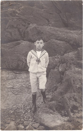 Garçon vêtu d'une marinière posant sur les rochers