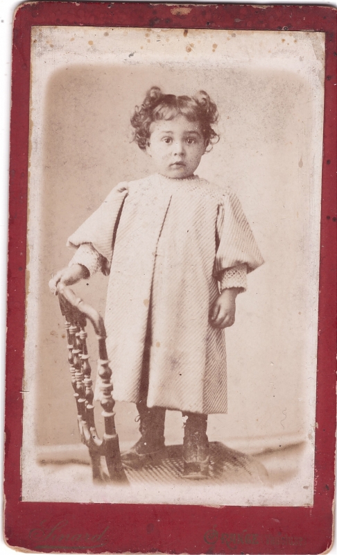 Enfant aux cheveux frisés debout sur une chaise