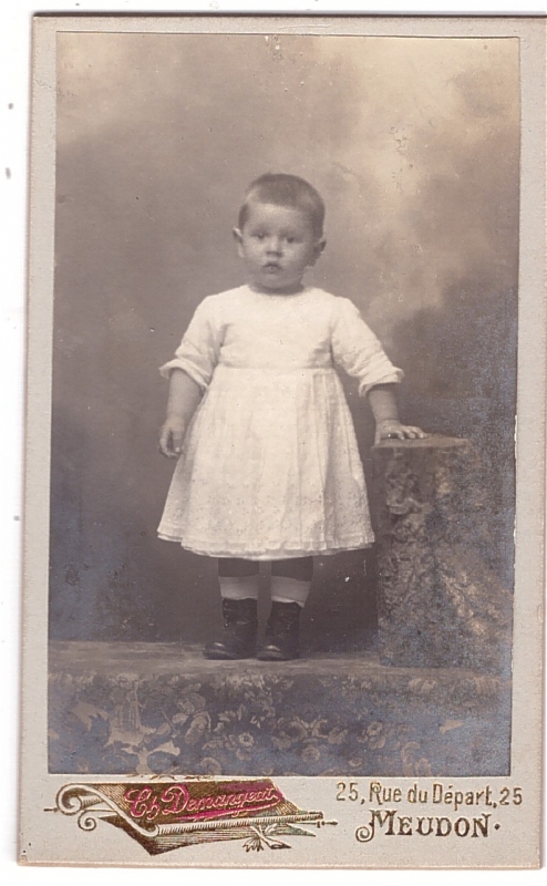 Enfant en robe blanche posant dans un décor d'atelier