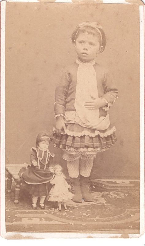Fillette posant à côté de ses poupées