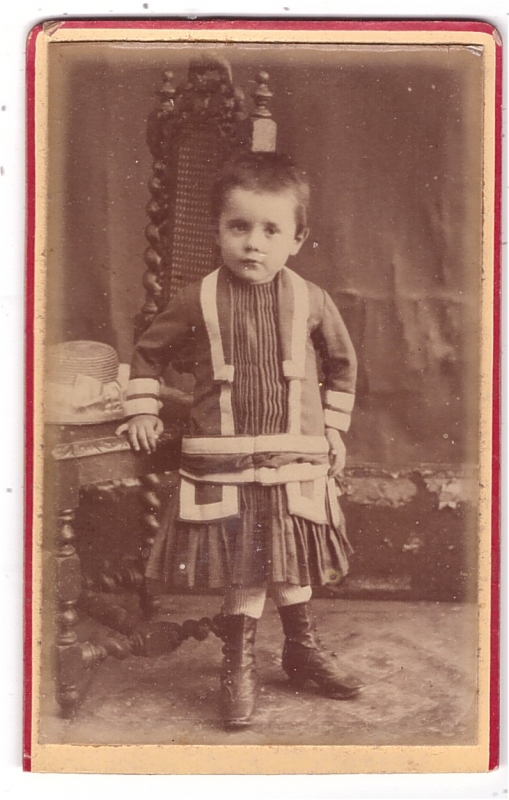 Enfant en robe debout près d'une chaise