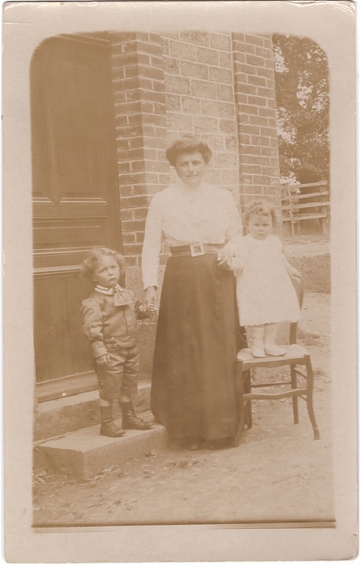 Femme posant devant chez elle avec deux jeunes enfants