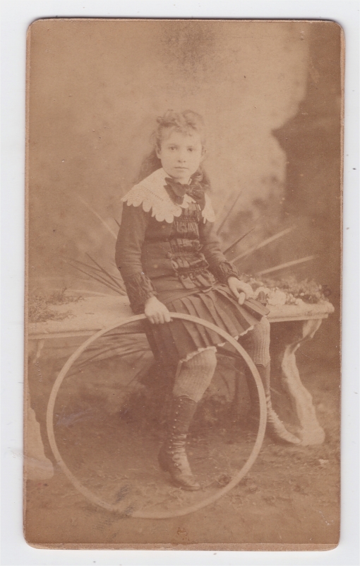 Fille assise sur un banc et tenant un cerceau