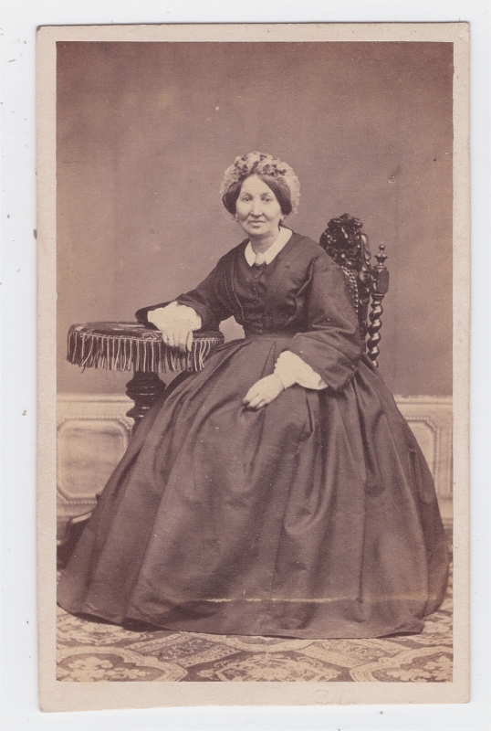 Femme assise, le bras reposant sur une petite table